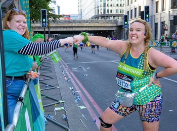 A female Samaritans London Marathon runner fist bumps a Samaritans volunteer cheerer during the race
