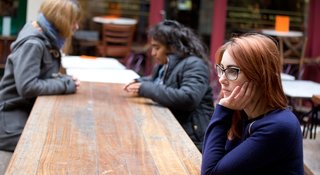 Woman sat on her own looking despondent - Samaritans