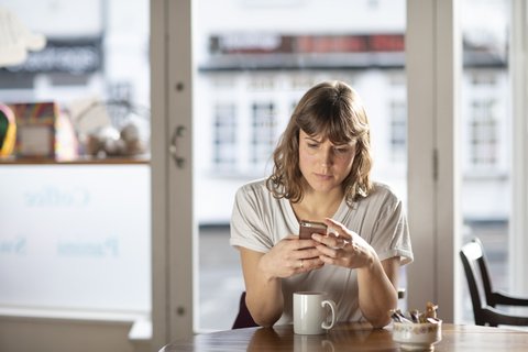 woman-reads-phone-cafe