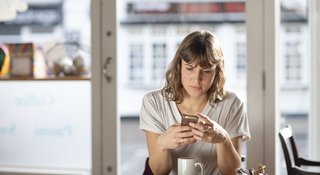 woman-reads-phone-cafe