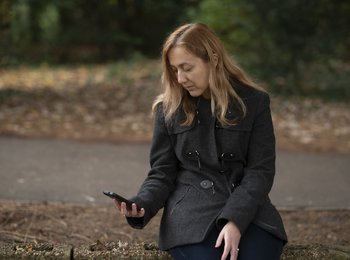 A woman sitting in a park looking at her phone