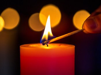 A hand lighting a candle with a mr