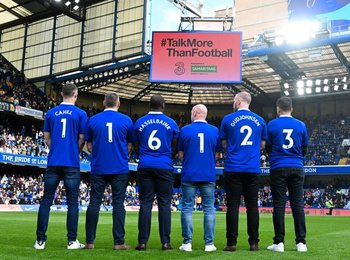 Footballers stand on the pitch during a match with 116 123 on the back of their shirts