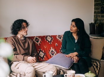 A man and a woman at home on the sofa having a conversation