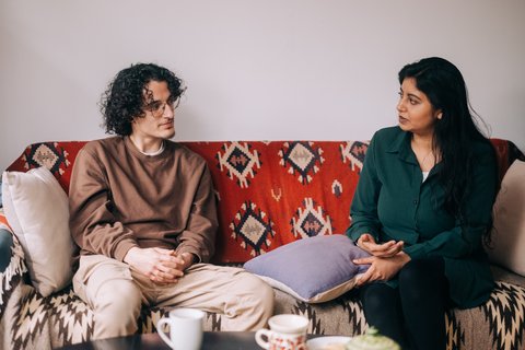 Two people sitting on a sofa talking