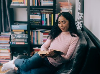 A woman reading a book on the sofa