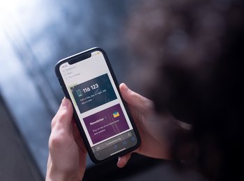 Hands holding a phone, on the screen is the Samaritans phone number