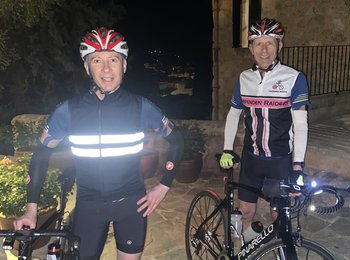 Two men stand next to two bikes.