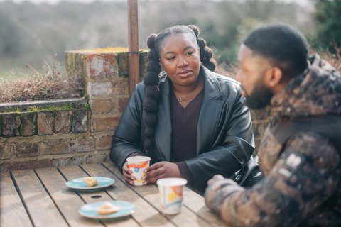 Two people sat outside talking on a bench (Outside_211_AR_)