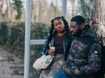 Two people sat at a train station talking