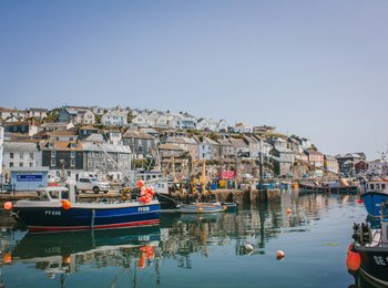A port filled with fishing boats surrounded by traditional Cornish fisherman's houses