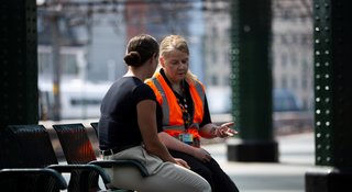 Two people talking on a bench at a train station