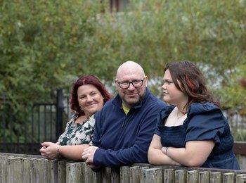 Kevin and his family are standing together on a bridge