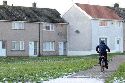 Child on bike outside a row of houses